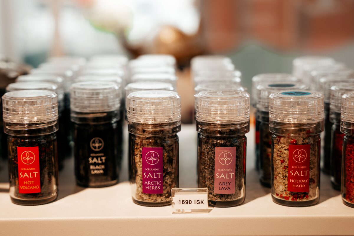 Rows of small jars of flavored Icelandic salt with red labels on a shop shelf.
