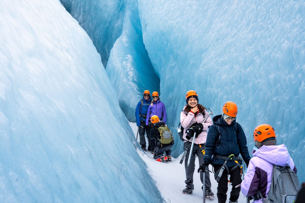 Guided group hiking with crampons on a blue Icelandic outlet glacier in summer.