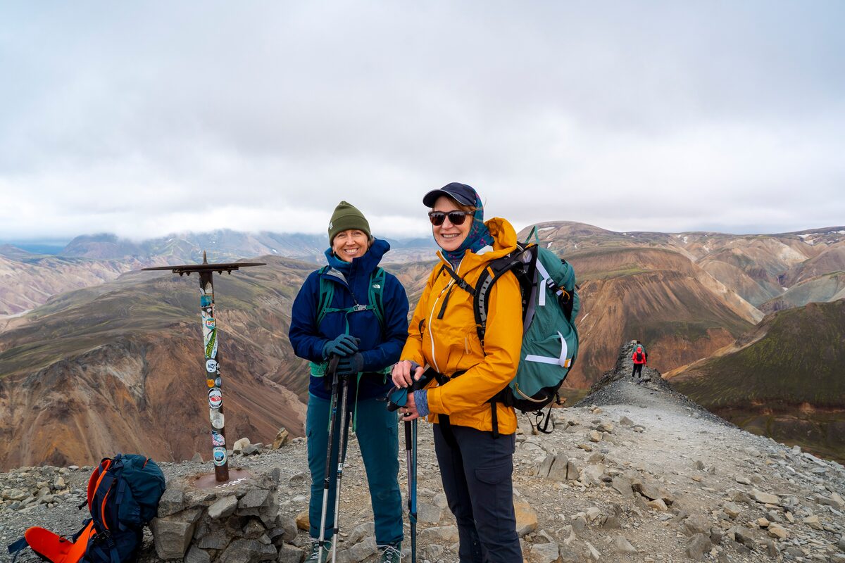 Two hikers in layered, waterproof clothing on an Icelandic trail in summer posing for the camera.