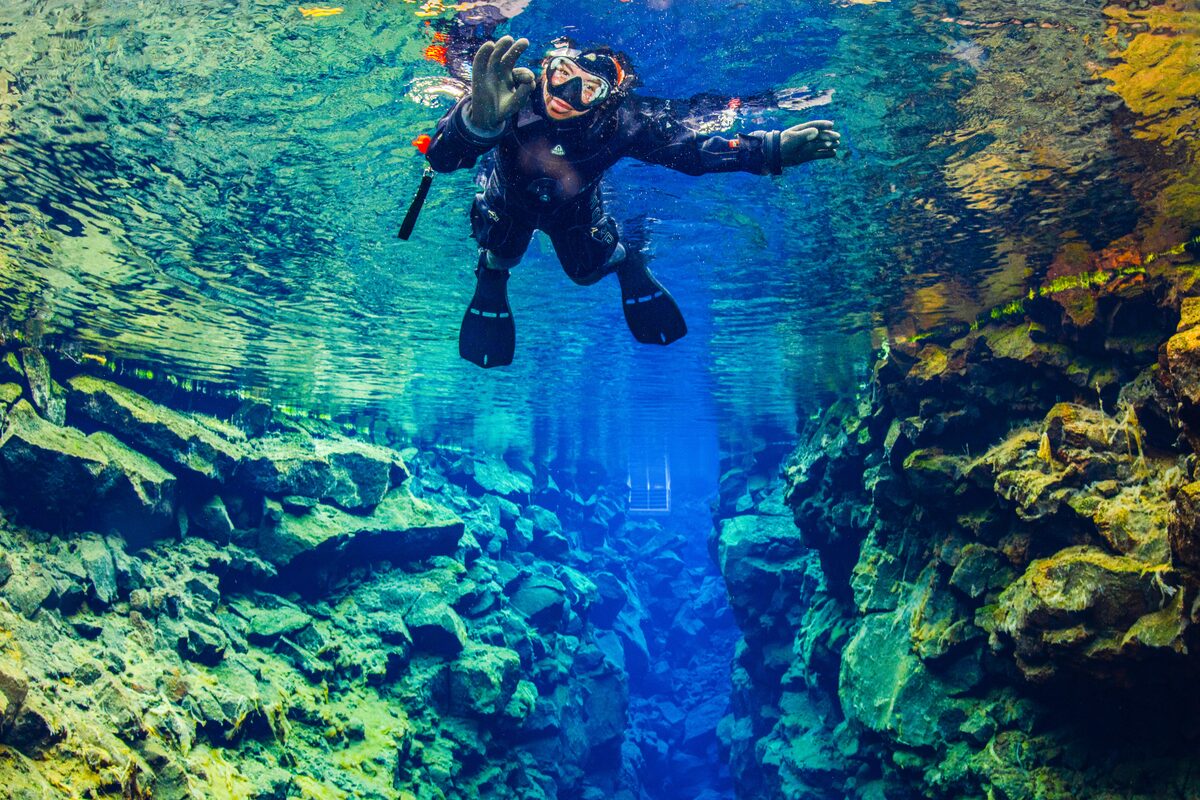 Snorkeler floating in the clear blue glacial water of the Silfra fissure.