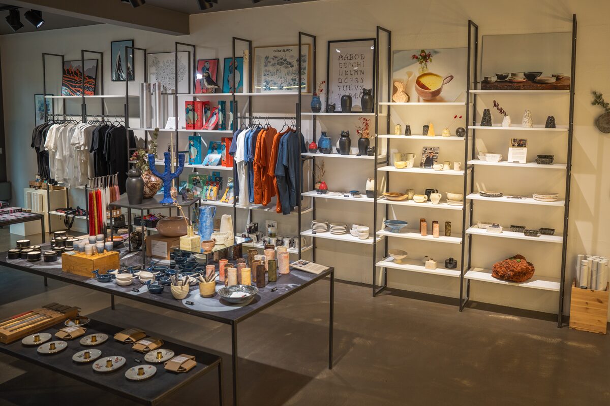 Interior of Rammagerðin in Reykjavík with Icelandic ceramics, clothing, art prints, candles, and design gifts displayed on shelves and tables.