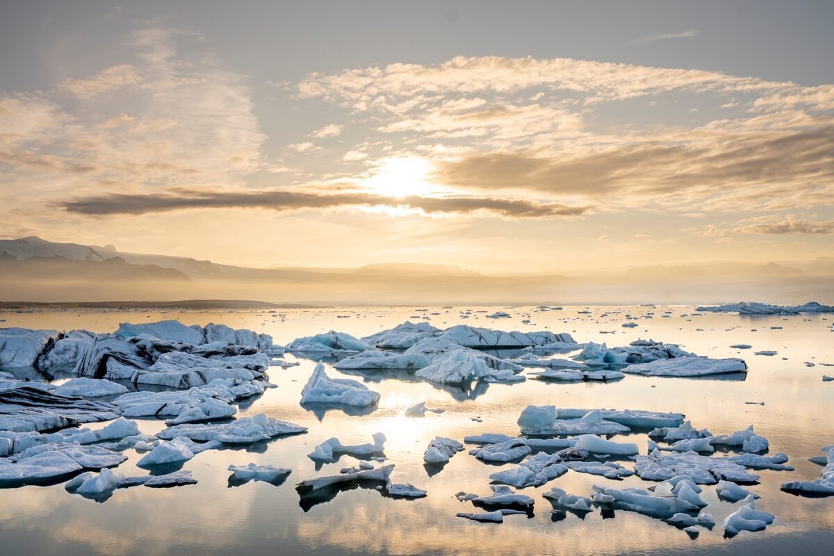 The midnight sun low over icebergs floating in Jökulsárlón glacier lagoon, Iceland.