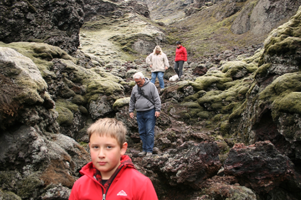 Family walking through rocky moss covered landscape by Laki Crater.