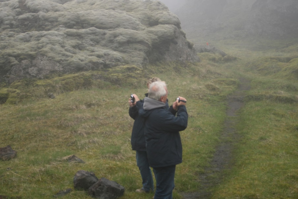 Two tourists taking photographs of Laki Crater surroundings in fog.