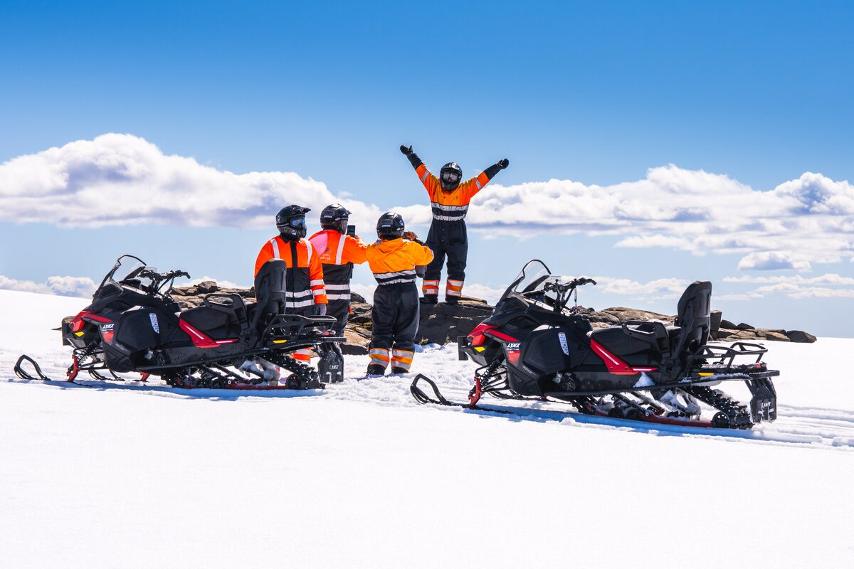 Small tour group at Langjokull glacier, posing on snowmobiles.
