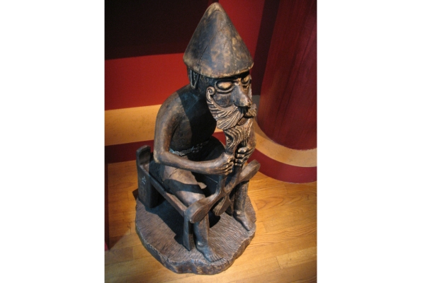 Bronze reproduction of the seated Eyrarland figure gripping a hammer to its chest. 