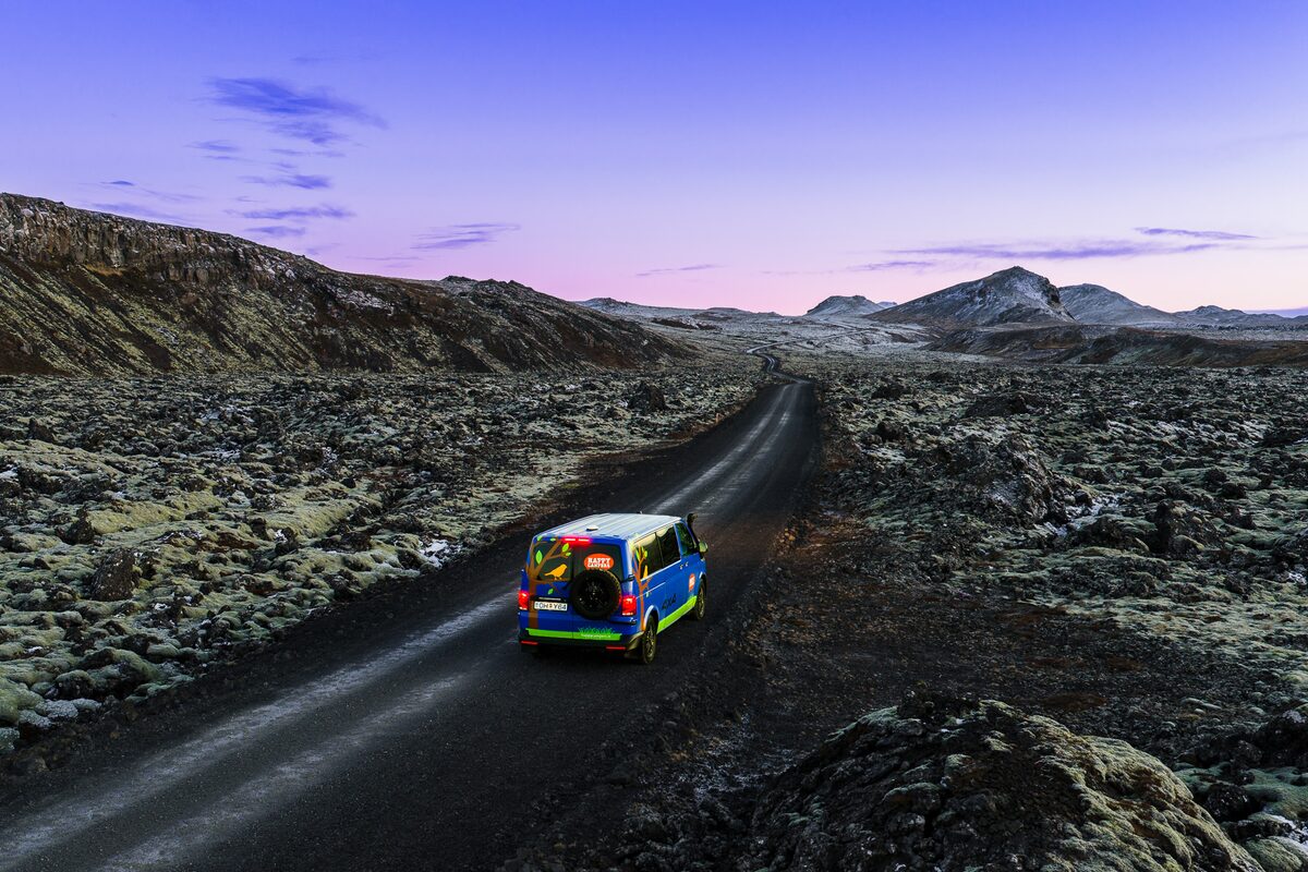 4x4 Medium blue campervan driving through frosty roads during early evening sky.