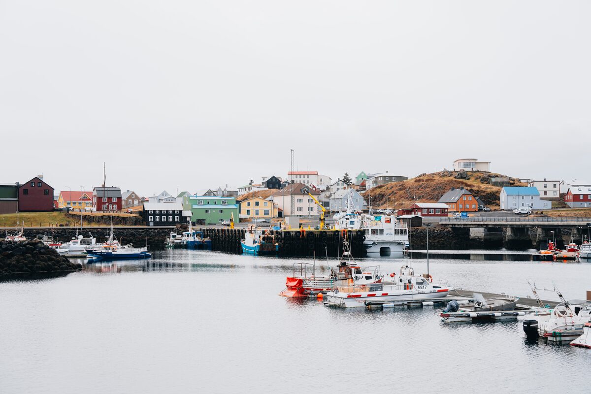 Boats moored in Stykkishólmur harbor below colorful timber houses on the hillside.
