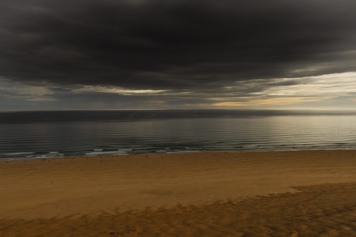 Darkness falling over a golden-sand beach during totality in the Westfjords.
