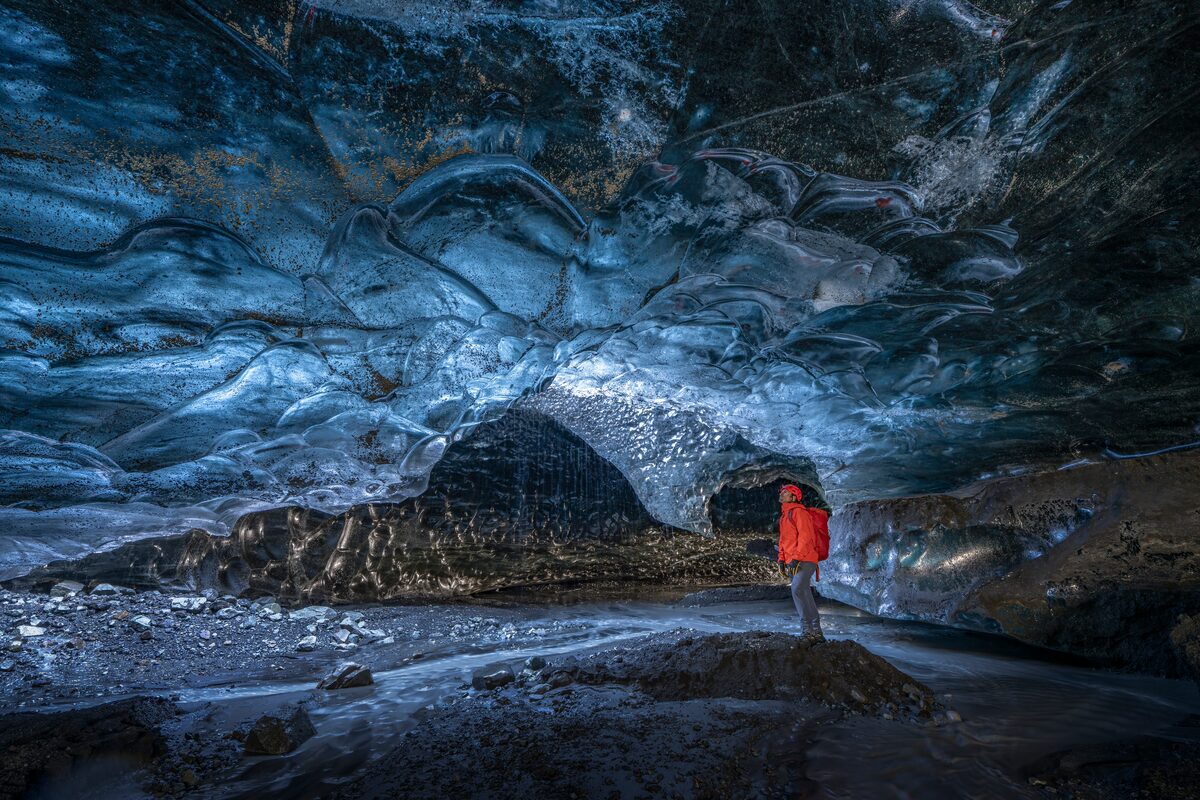 Male tourist viewing crystal formations inside crystal ice cave in Iceland.
