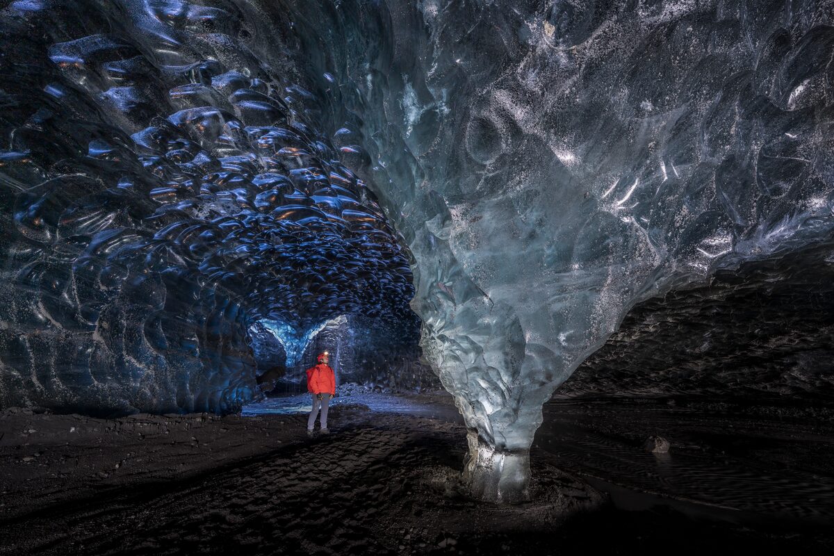 Male tourist standing inside crystal ice cave in Iceland, 2026.
