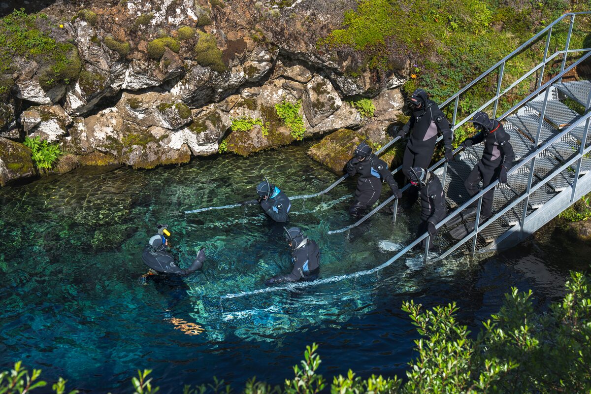 Snorkelers entering Silfra fissure from the metal platform at Thingvellir National Park