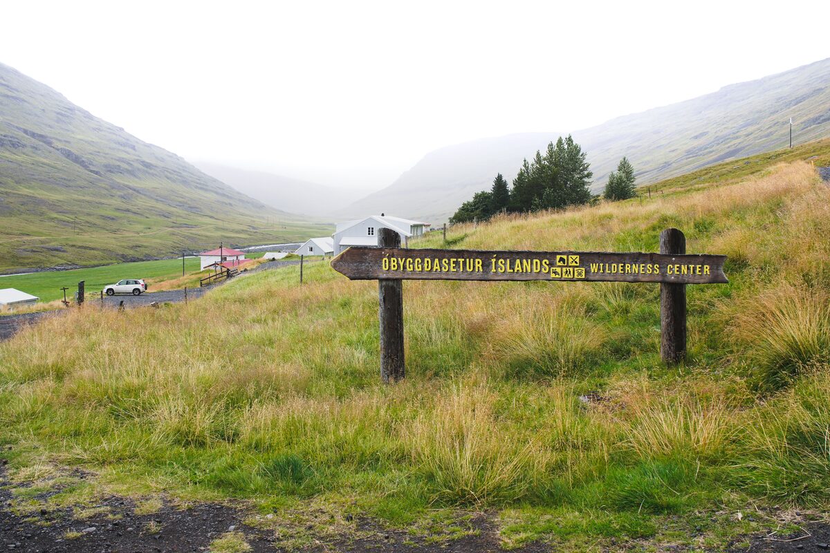 Wooden Wilderness Center sign in a grassy valley with farm buildings below.