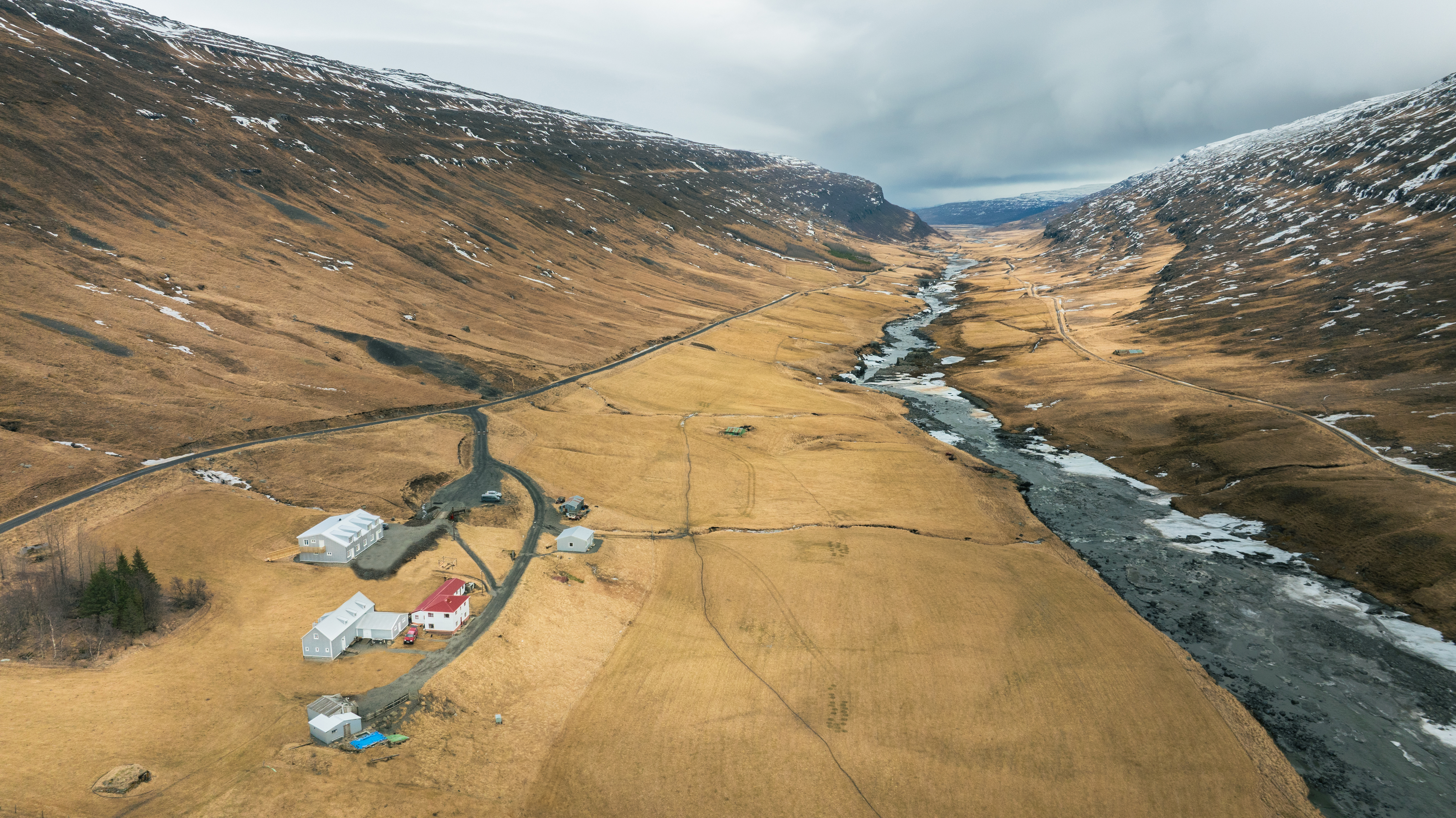 Wilderness Center buildings beside the Jökulsá river in Norðurdalur valley with patchy snow.