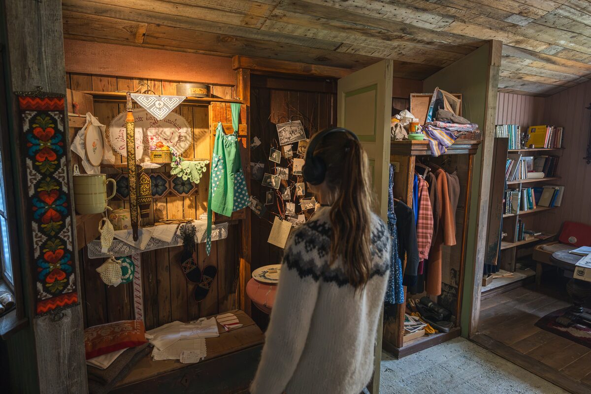 Visitor wearing headphones views textiles and household objects in the Wilderness Center exhibition.