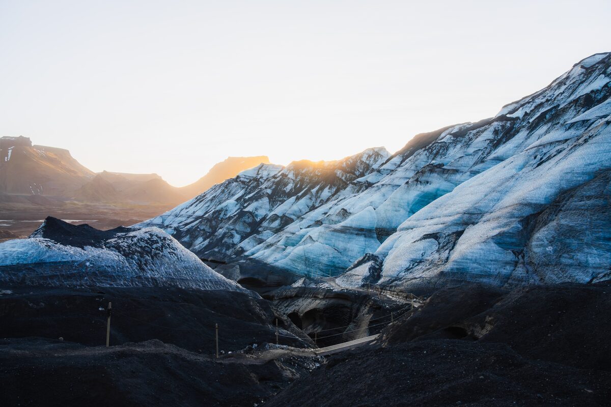 Ash-streaked glacier ice above black volcanic sand in South Iceland.
