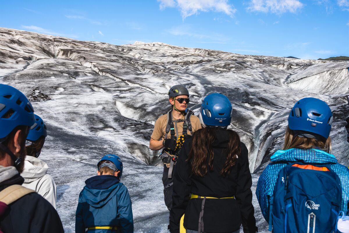 Tour guide instructing small group of glacier hikers on Solheimajokull glacier