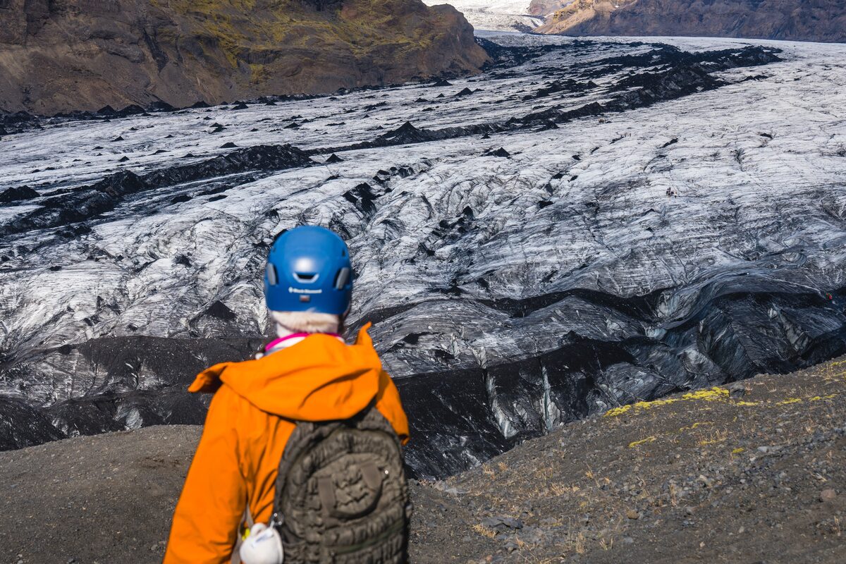 Single tourist viewing Solheimajokull ash covered glacier crevasses