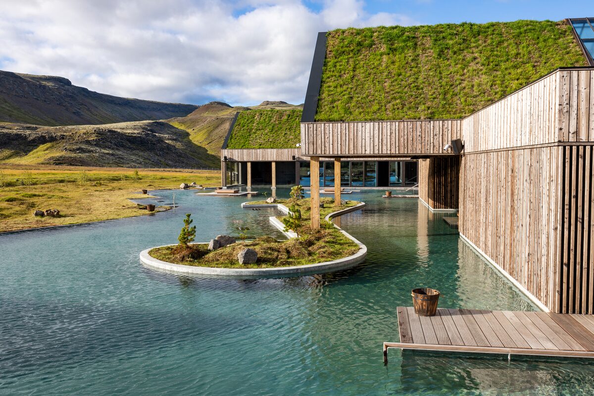 Reykjabod hot springs with grass roof building and beautiful views of Icelandic landscape.