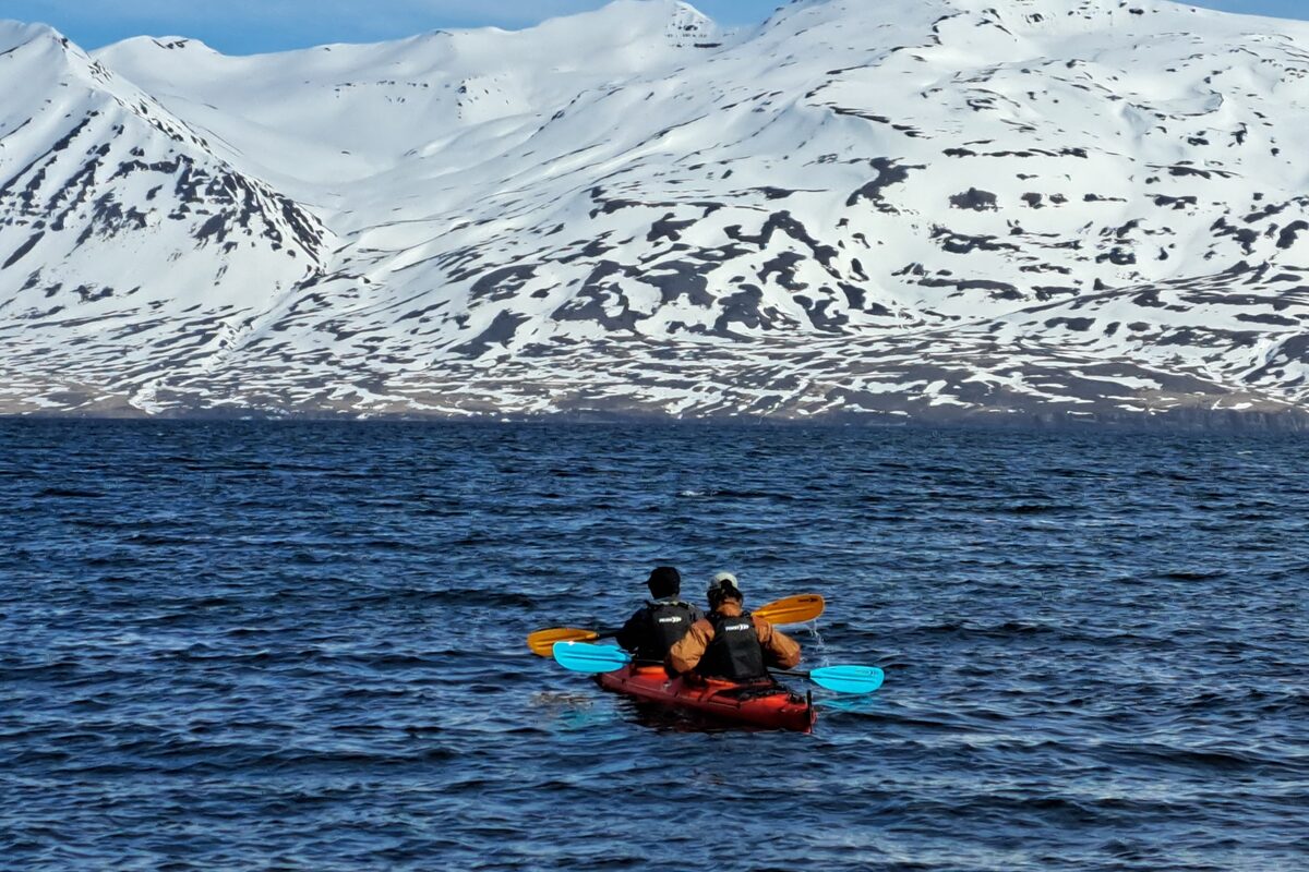 Two People In A Kayak With A Snowy Mountain In The Background in Iceland
