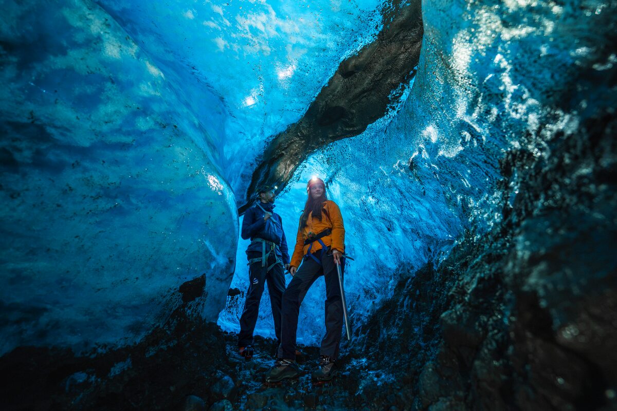 People Standing Between Ice Walls At Blue Ice Cave in Iceland