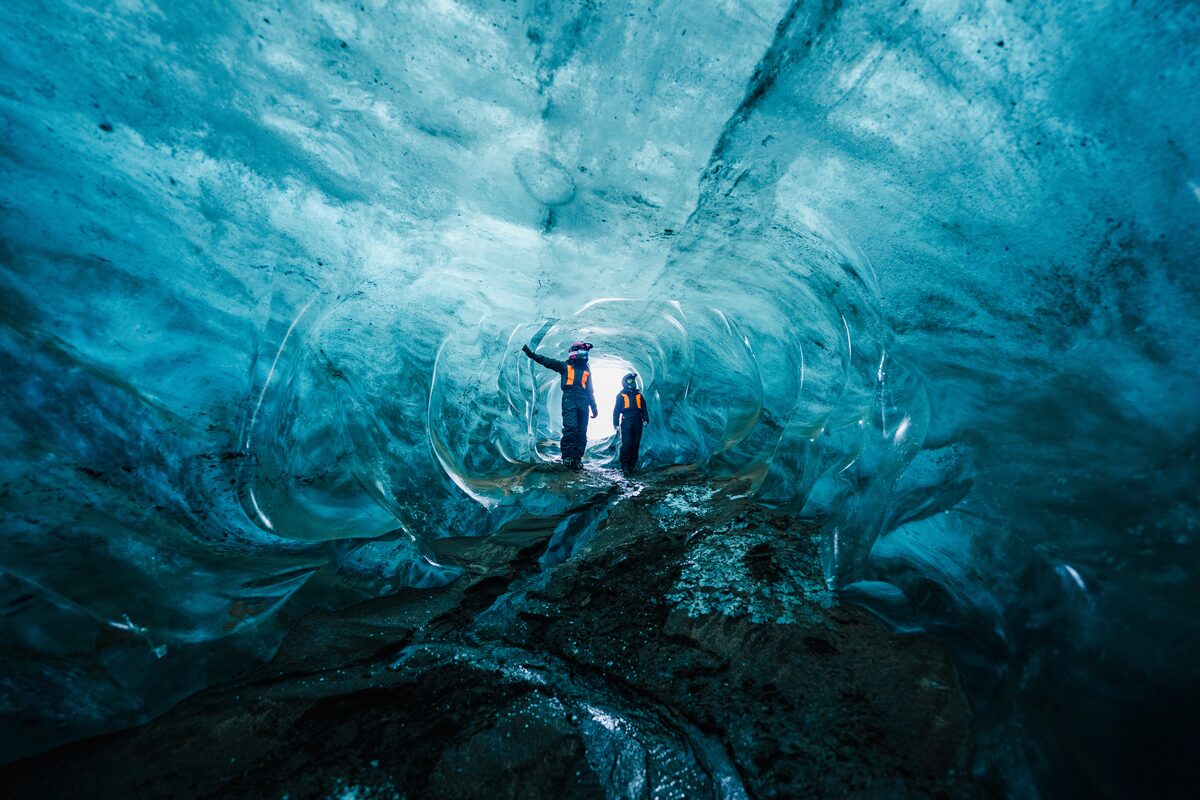 Two snowmobilers inside Neptune ice cave at Langjokull glacier.