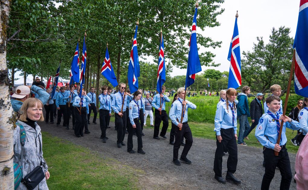 Scouts carrying Icelandic flags march through a Reykjavík park during National Day celebrations.