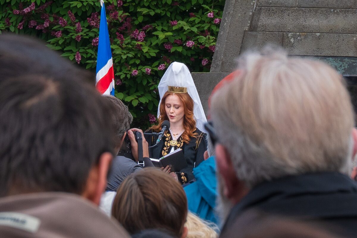 Fjallkona in traditional Icelandic dress reads from a folder before a crowd at Austurvöllur.