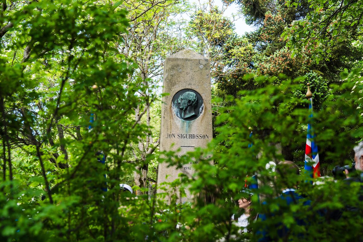 Jón Sigurðsson’s grave marker with bronze profile medallion among trees in Hólavallagarður cemetery.