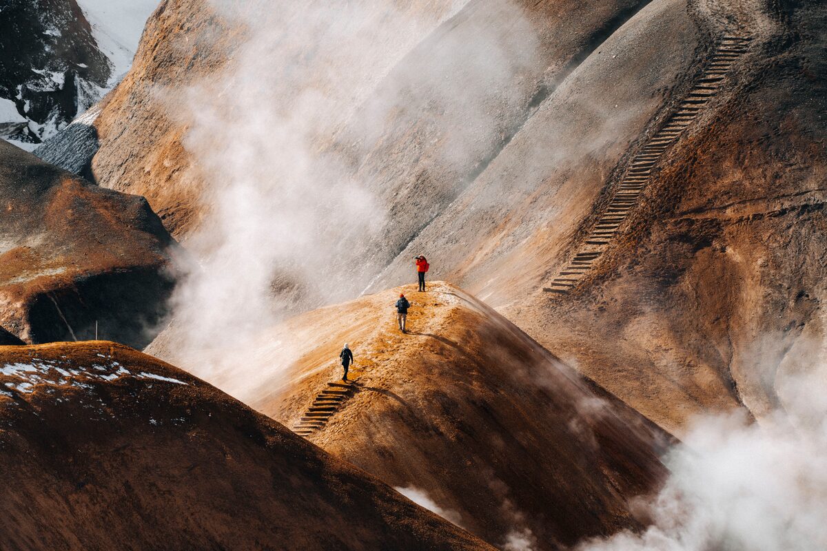 Hikers on wooden steps across steaming orange slopes at Hveradalir in Kerlingarfjöll.