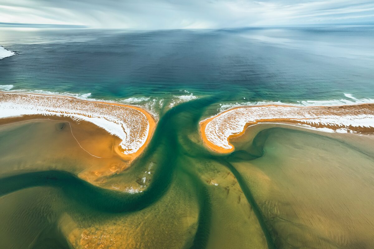 Aerial view of two sand spits and winding green channels where Rauðasandur meets the sea.