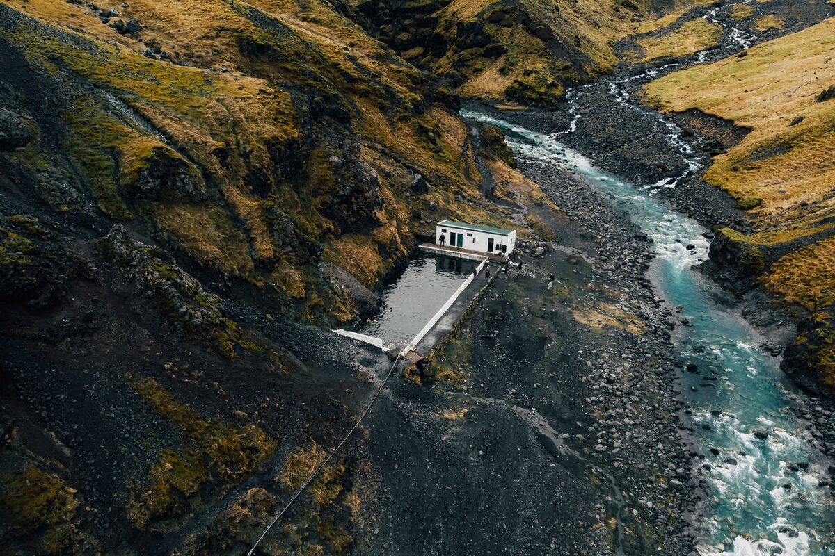 Seljavallalaug pool below a steep green mountainside in South Iceland.