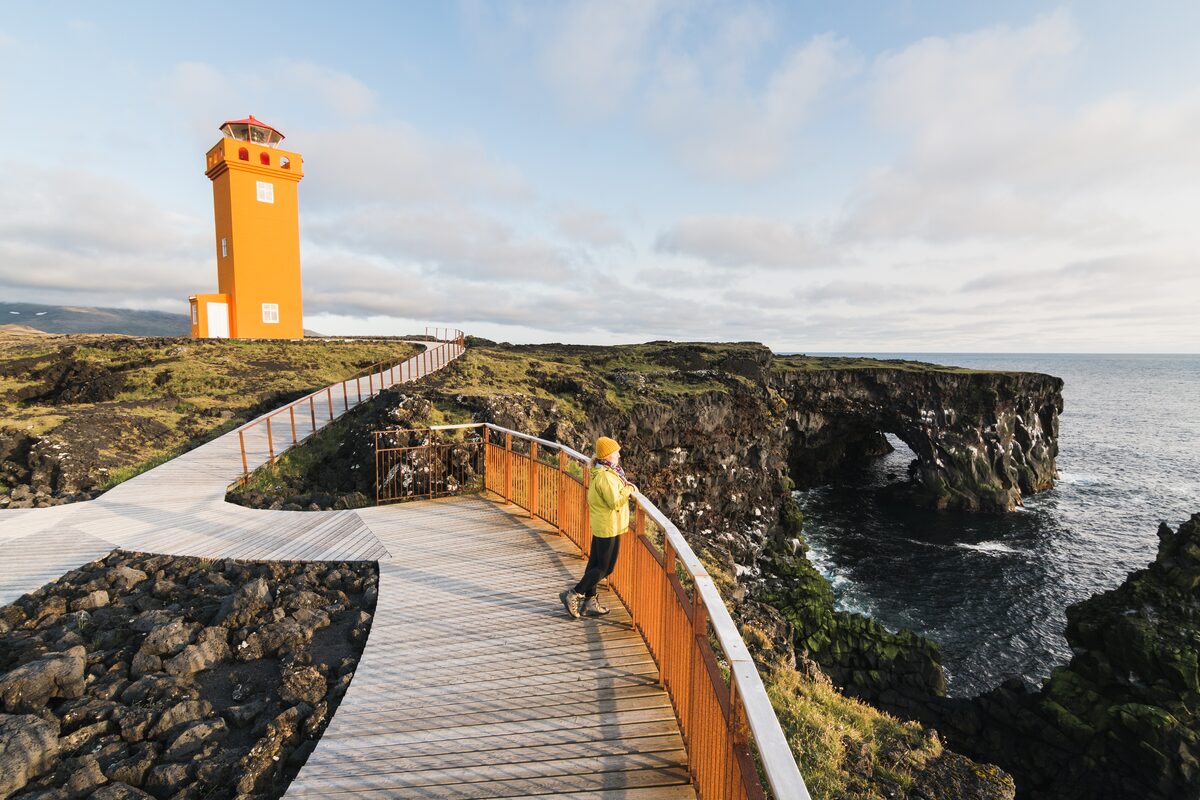 Bright orange Svörtuloft lighthouse on black lava cliffs at the tip of Snæfellsnes Peninsula.