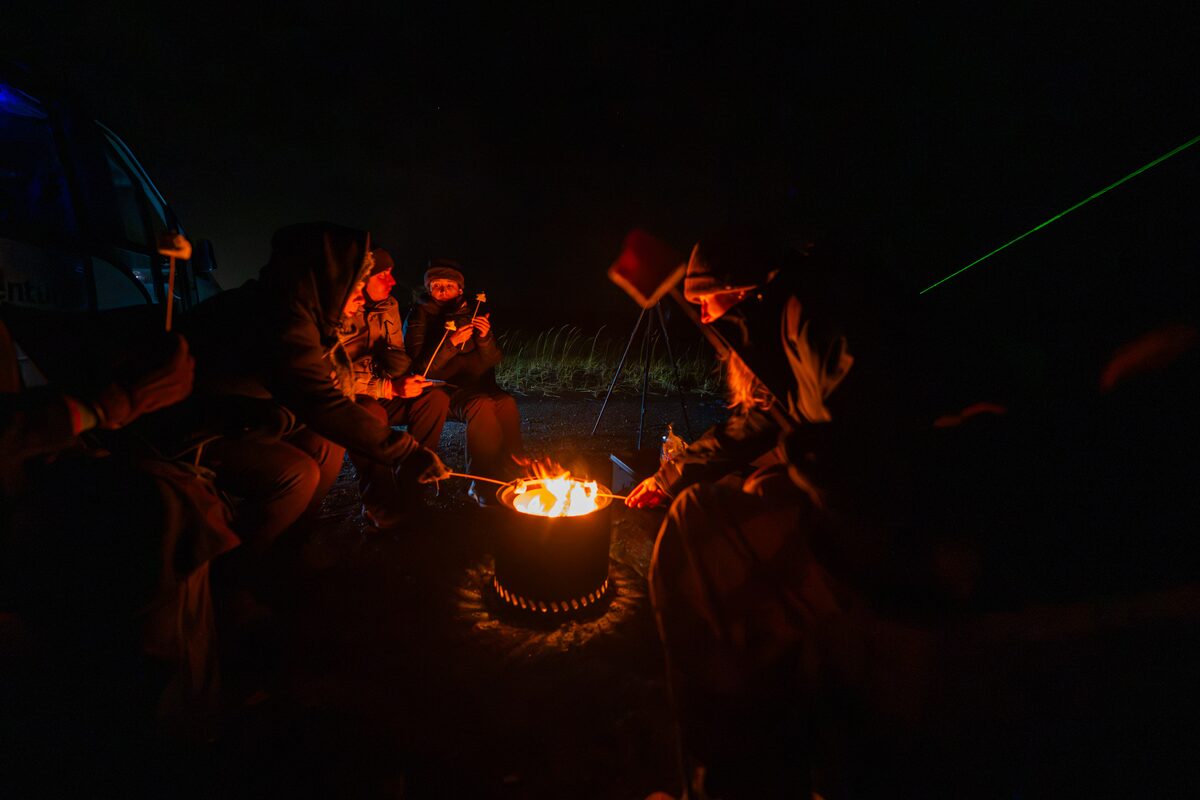 People Talking And Roasting Marshmallows On A Campfire in Iceland