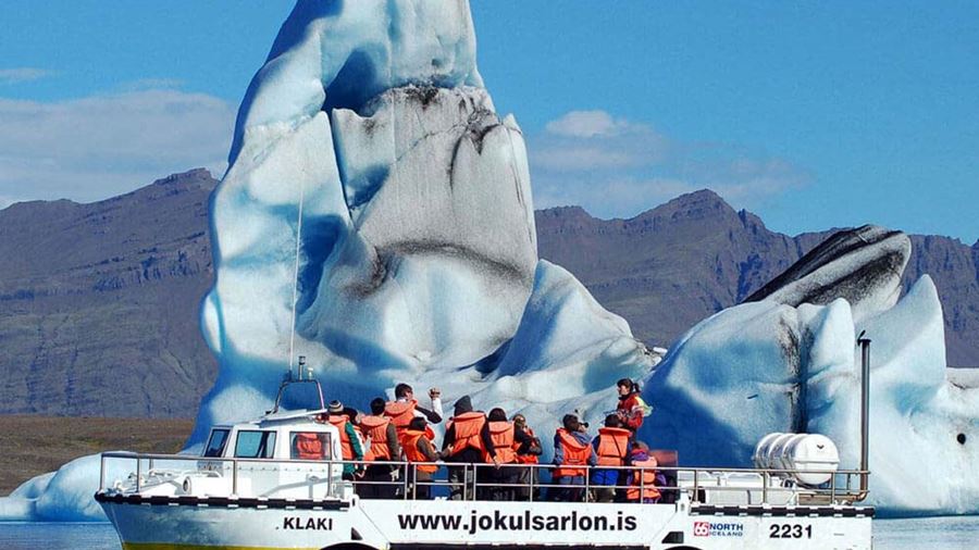 boat full of people by huge iceberg