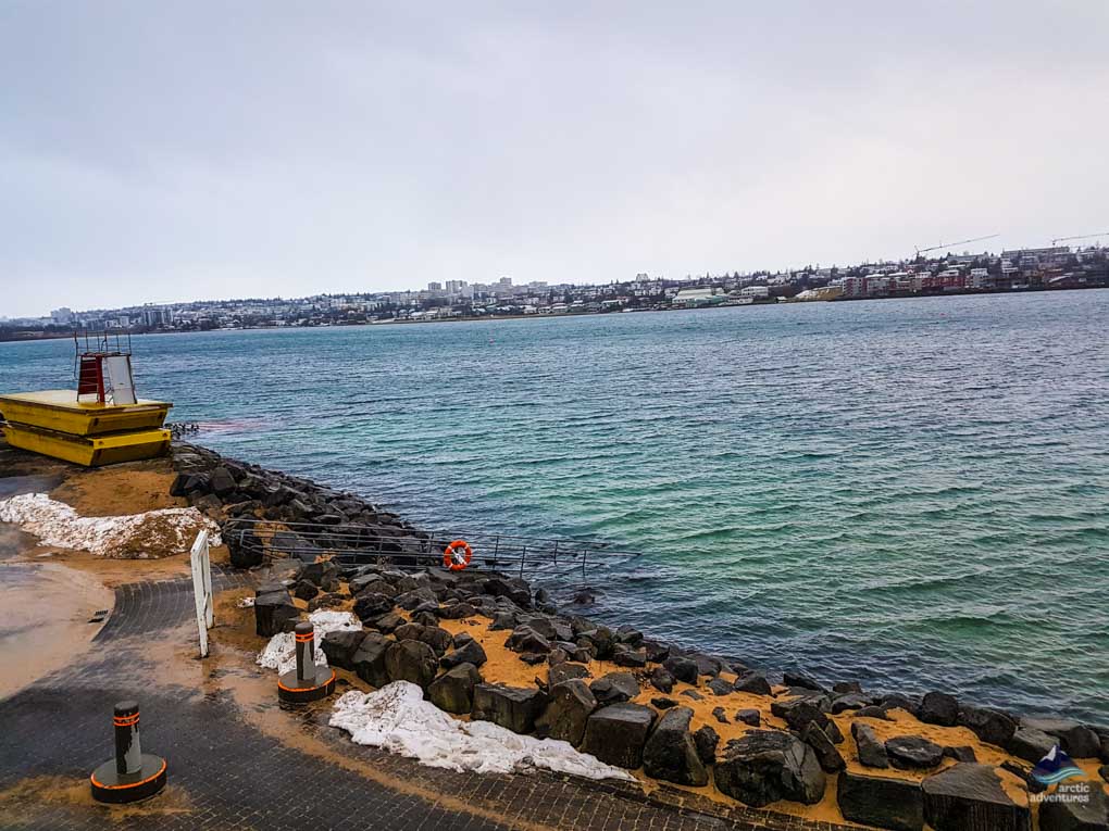 View of the city in a horizon and black rocks on the shore