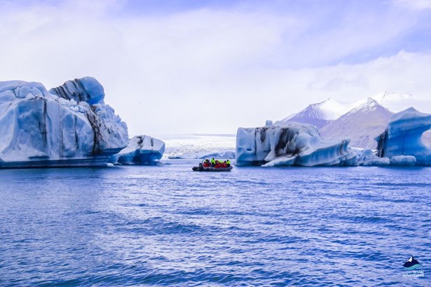 boat swimming between icebergs in glacier lagoon
