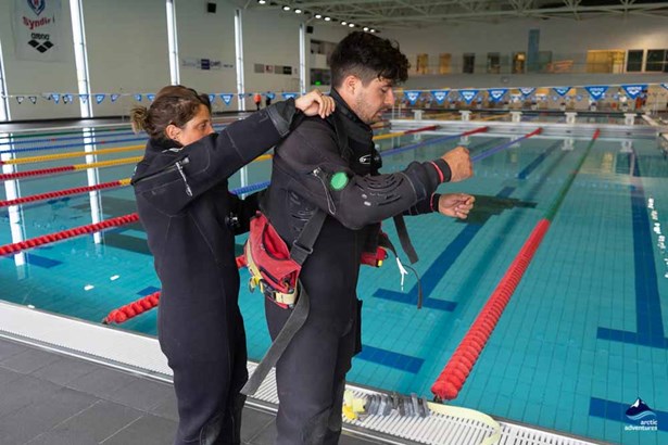 instructor putting dry suit for diving student