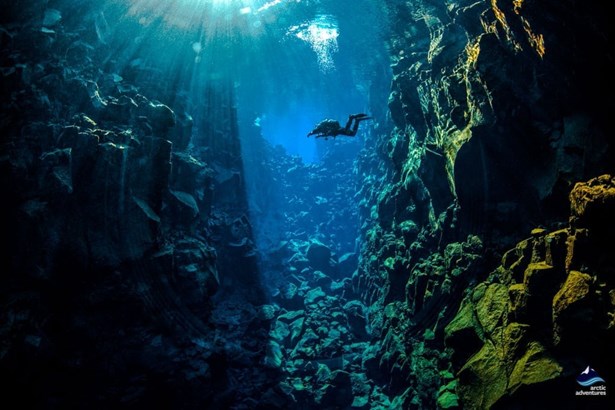 man diving in deep rocks crack Iceland